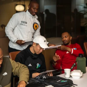 Coach Emmanuel reviewing a training plan at a table during a consulting session