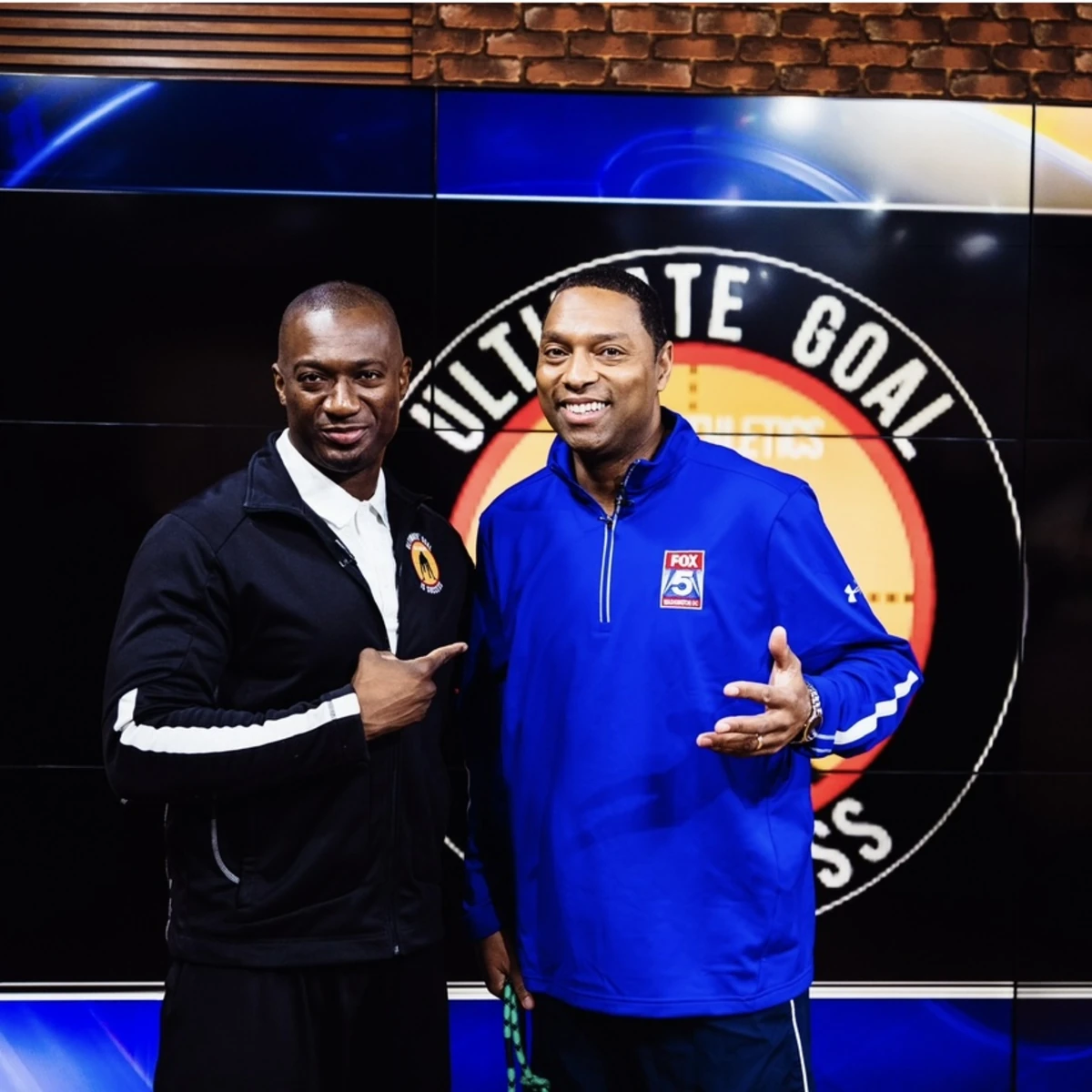 Coach Emmanuel on a television studio set with the UGIS Athletics backdrop